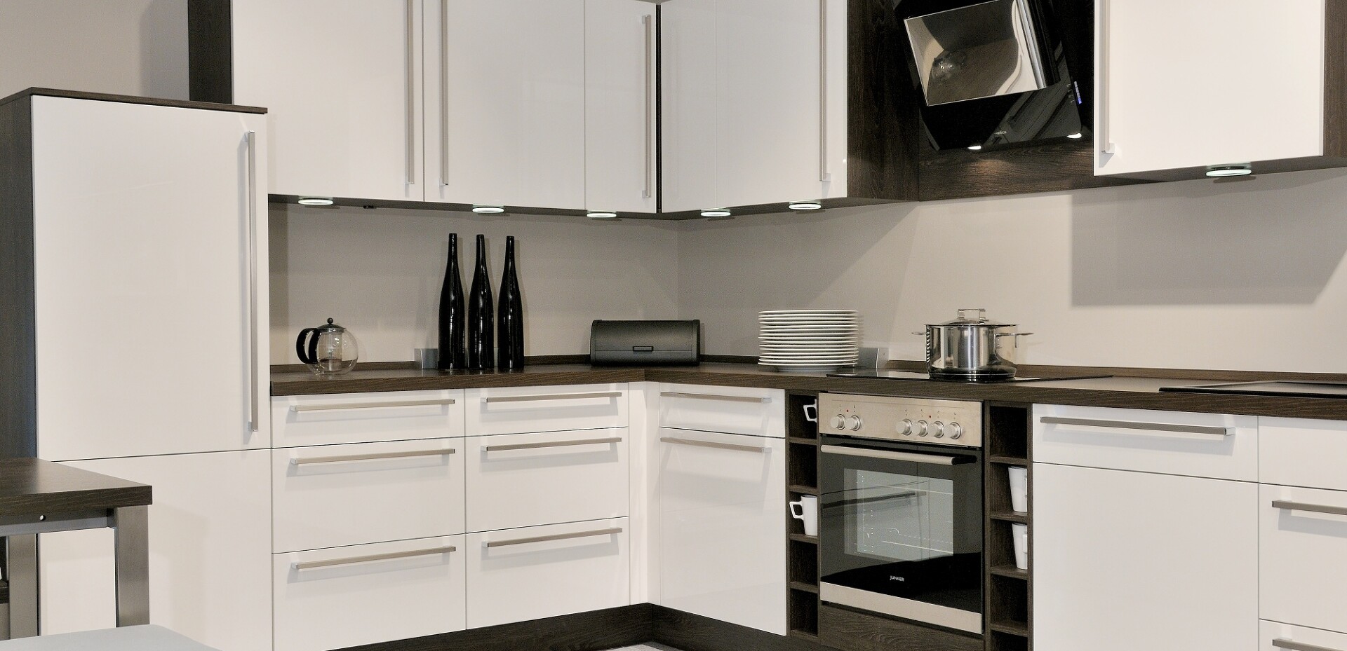 Zeitlose weiße Küche mit moderner Dunstabzugshaube für geruchloses Kochen.